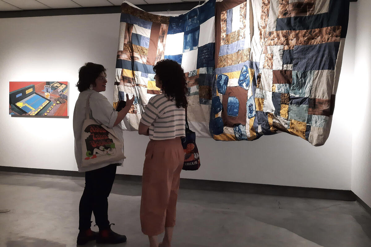 Two people standing in front of a quilt art piece
